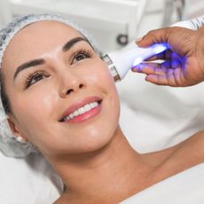 a woman on a clinic bed getting a facial laser treatment