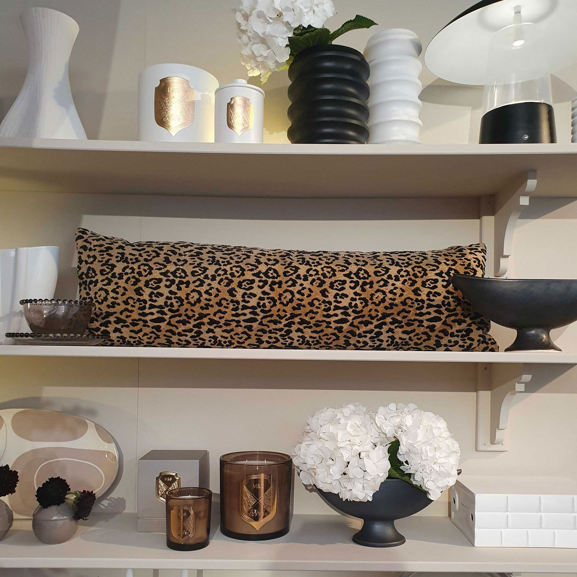 Leopard print bolster cushion on white open shelving