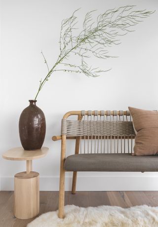 White entryway with earthy bench and side table with decor