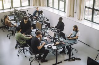 High angle view of male and female programmers working on computers at desk in office.