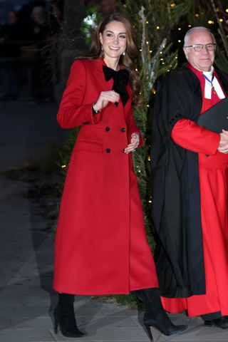 Princess Kate arrives at her annual Christmas concert wearing a red dress with a bow and black pointed toe boots