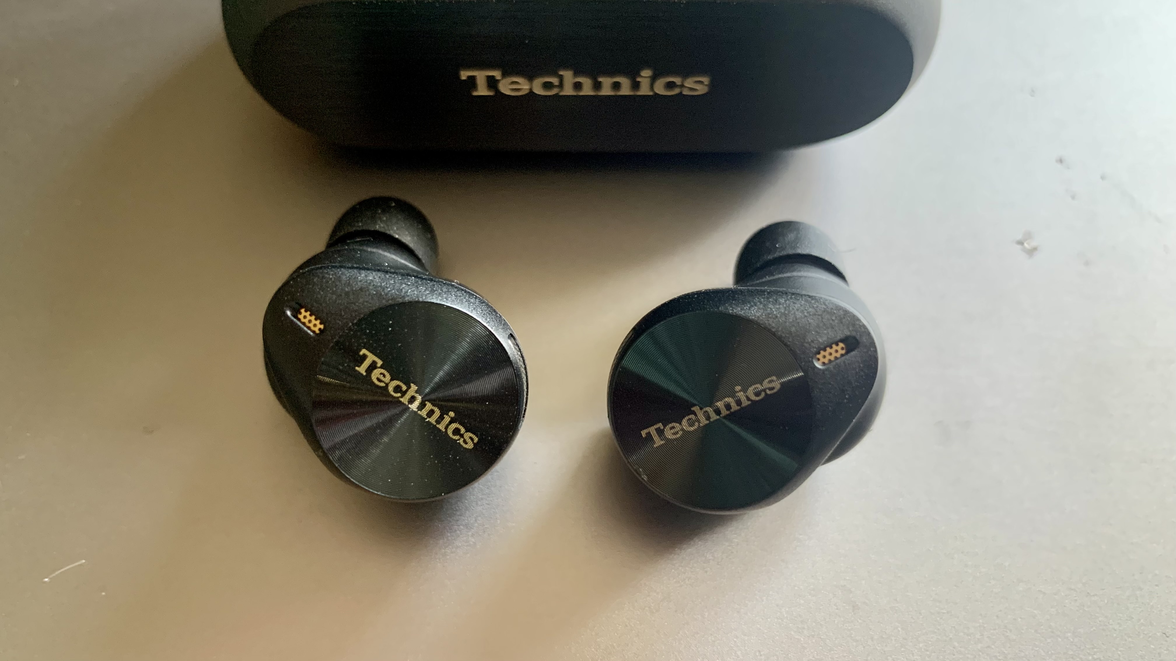 Technics EAH-AZ80 earbuds and case on a brown table