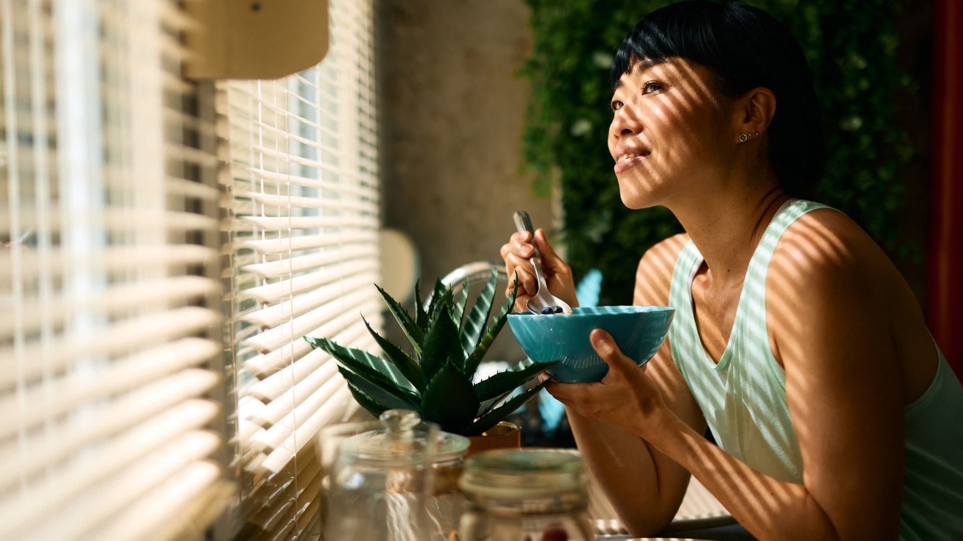 Woman eating bowl of cereal in kitchen 