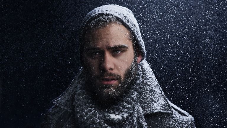 Man wearing one of the best scarves for men getting snowed on