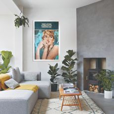 A living room with a grey sofa with a chaise and a complementing darker grey feature wall with a wood-burning stove