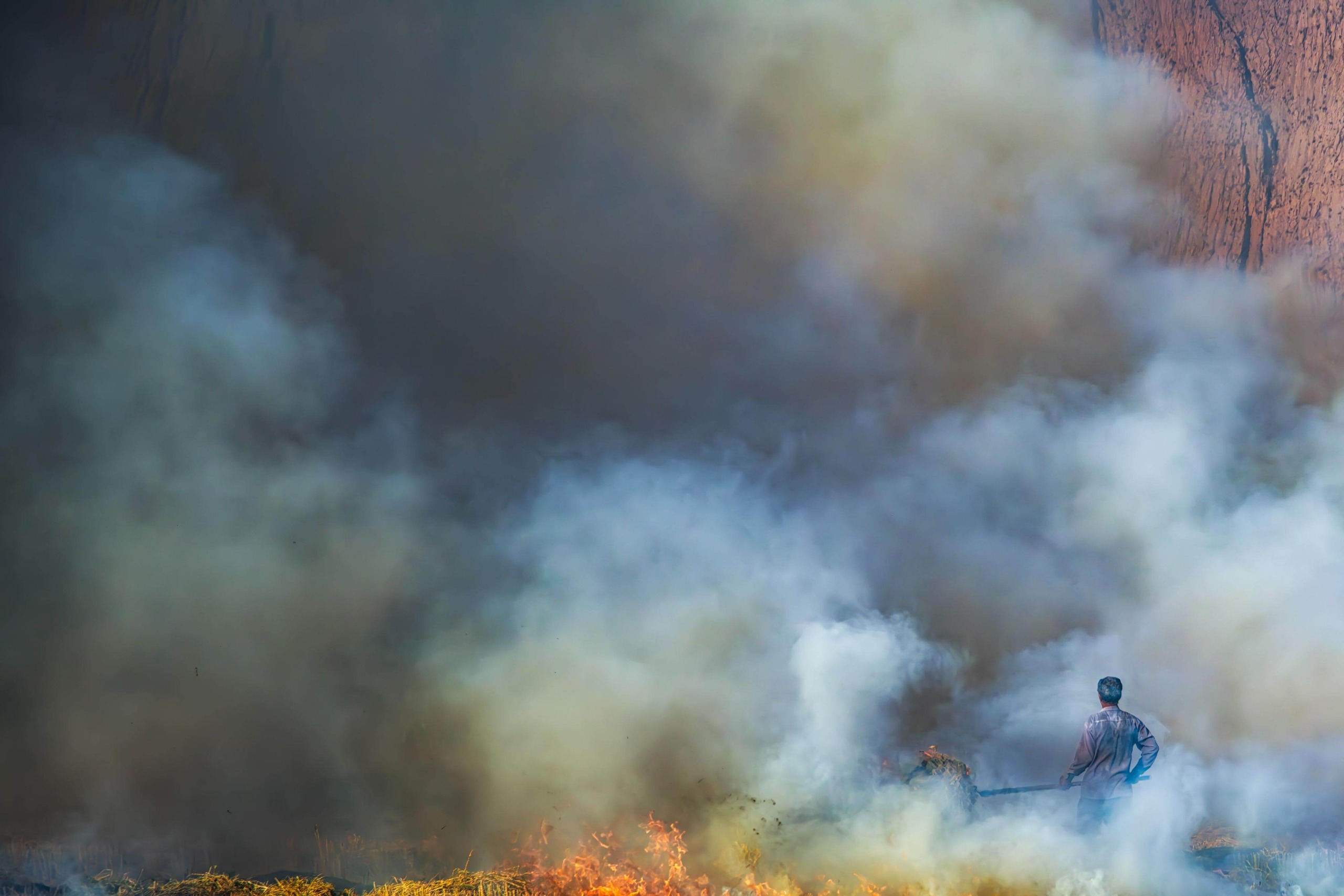 Farmer stood among shroud of smoke burning his land.