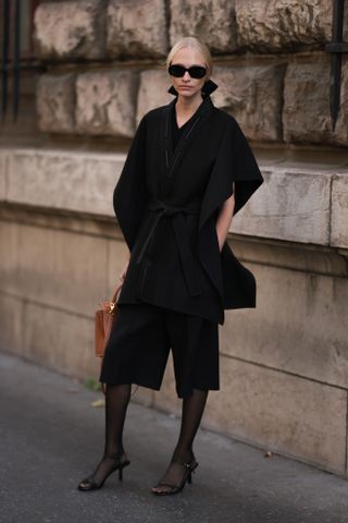 woman wearing coat, bermuda shorts, tights, and heels