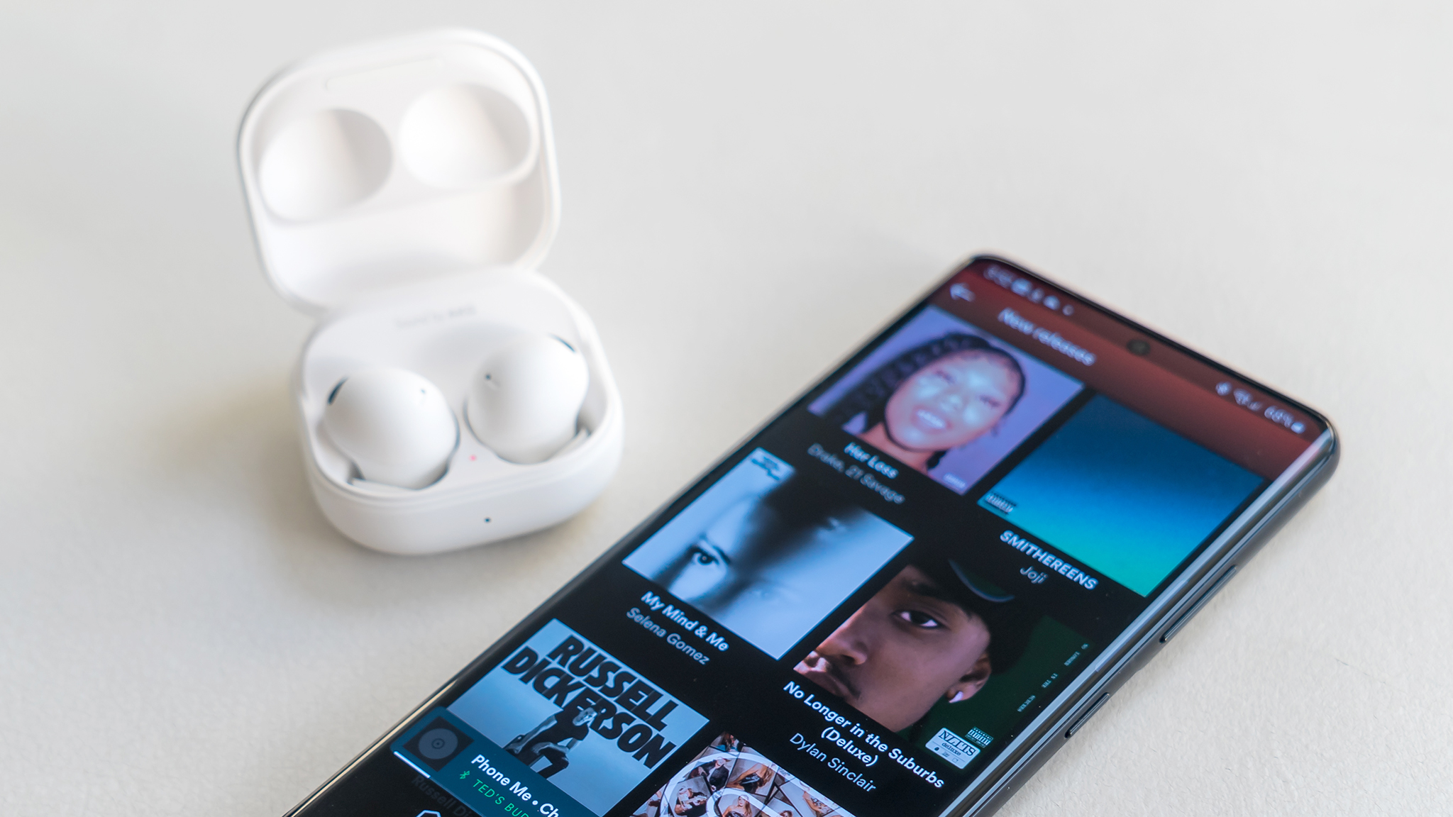 Samsung Galaxy Buds 2 Pro next to Spotify app on phone.