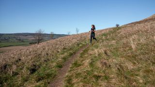 Woman doing hill training on grassy hill in the sunshine