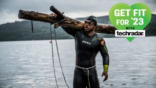 Ross Edgley carries a tree into the water before a 10K swim at Lake Windemere 