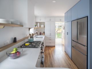 A kitchen with blue cabinets and light wood flooring