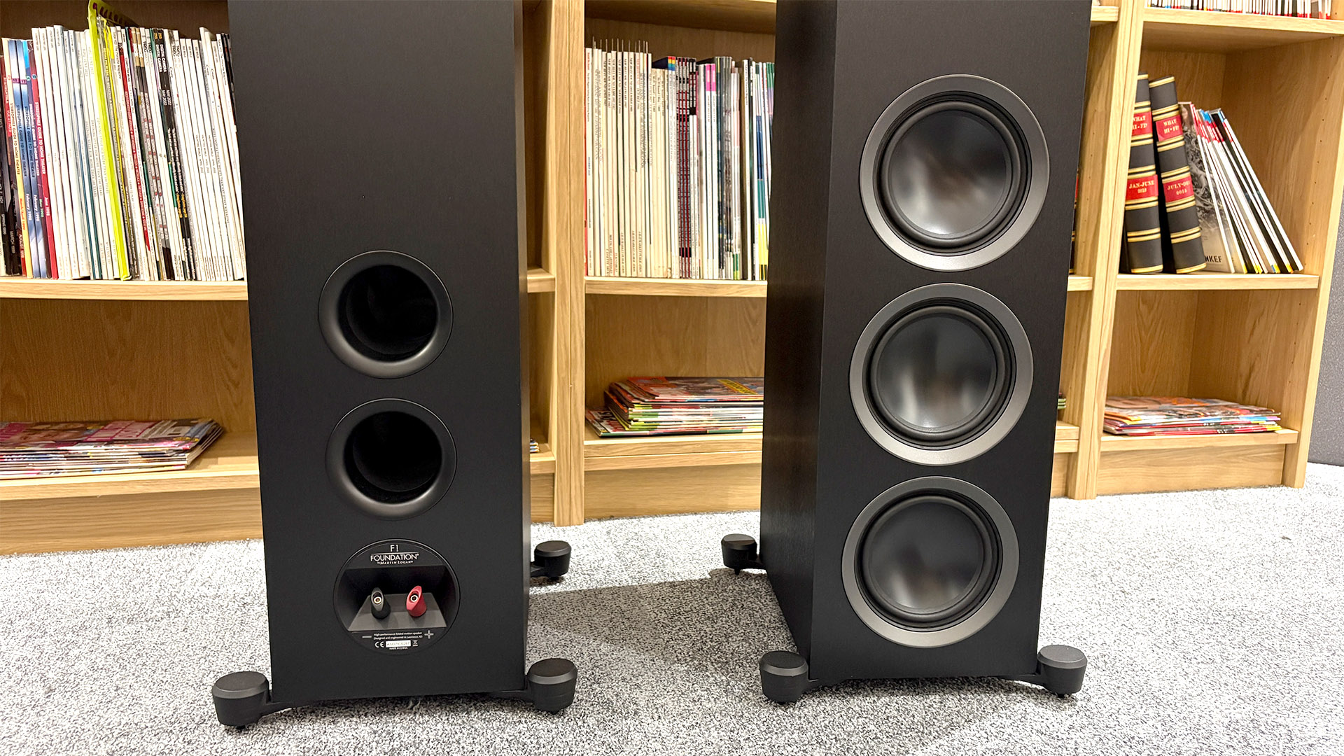 Martin Logan Motion Foundation F1 floorstanding speakers in front of bookcase, one it turned around to show binding posts