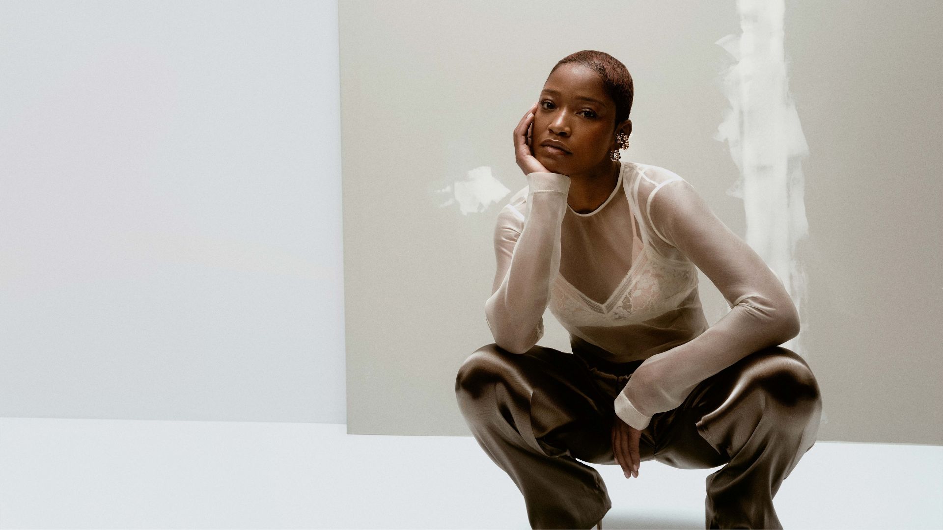 Keke Palmer wearing black pants and a white sheer top over a white bralette