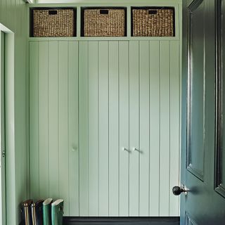 Entrance hall boot room area with green panelled walls and doors