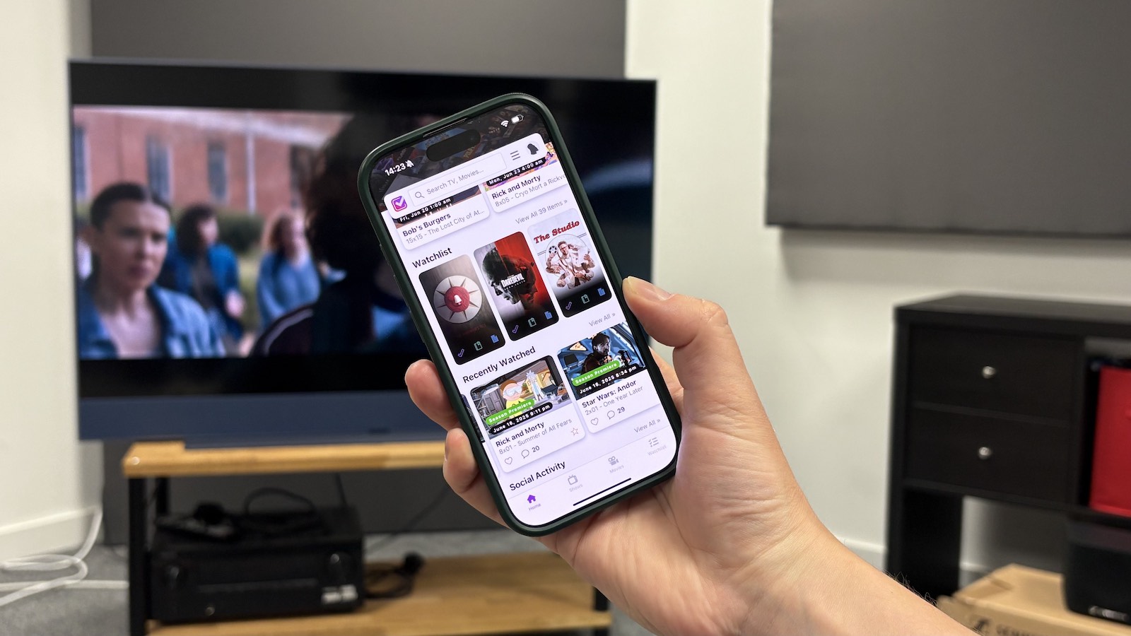 A photo of someone holing an iPhone with the Trakt app open.