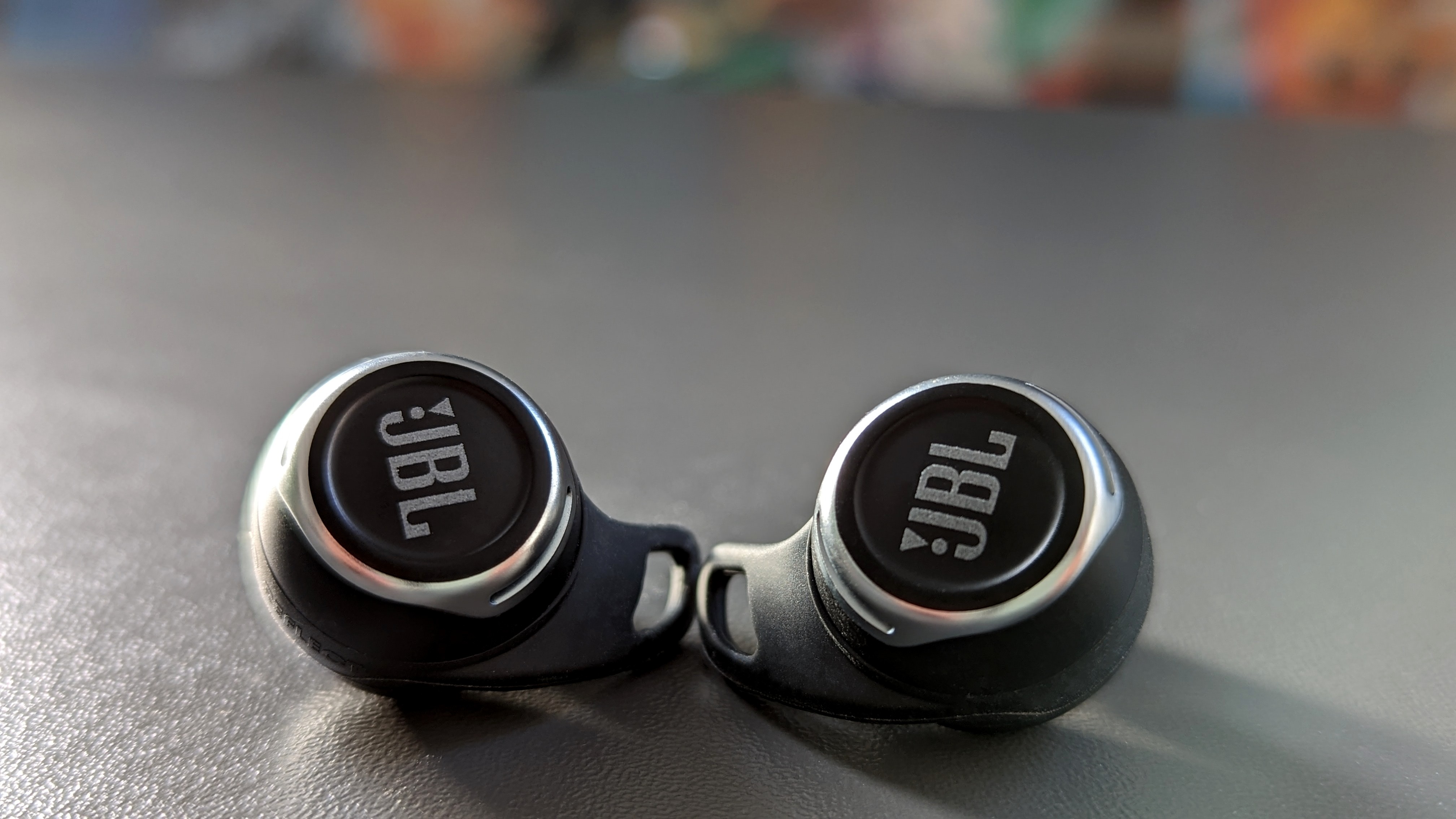JBL Reflect Flow Pro høretelefonerne ligger side om side med logoet mod os på et gråt bord