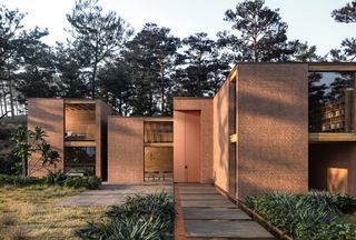 Modern brick residence with double-height terracotta-hued door by Oikos