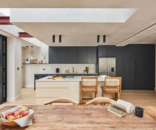 a modern kitchen extensions with black and white cabinetry, and skylights running around the periphery of the room.