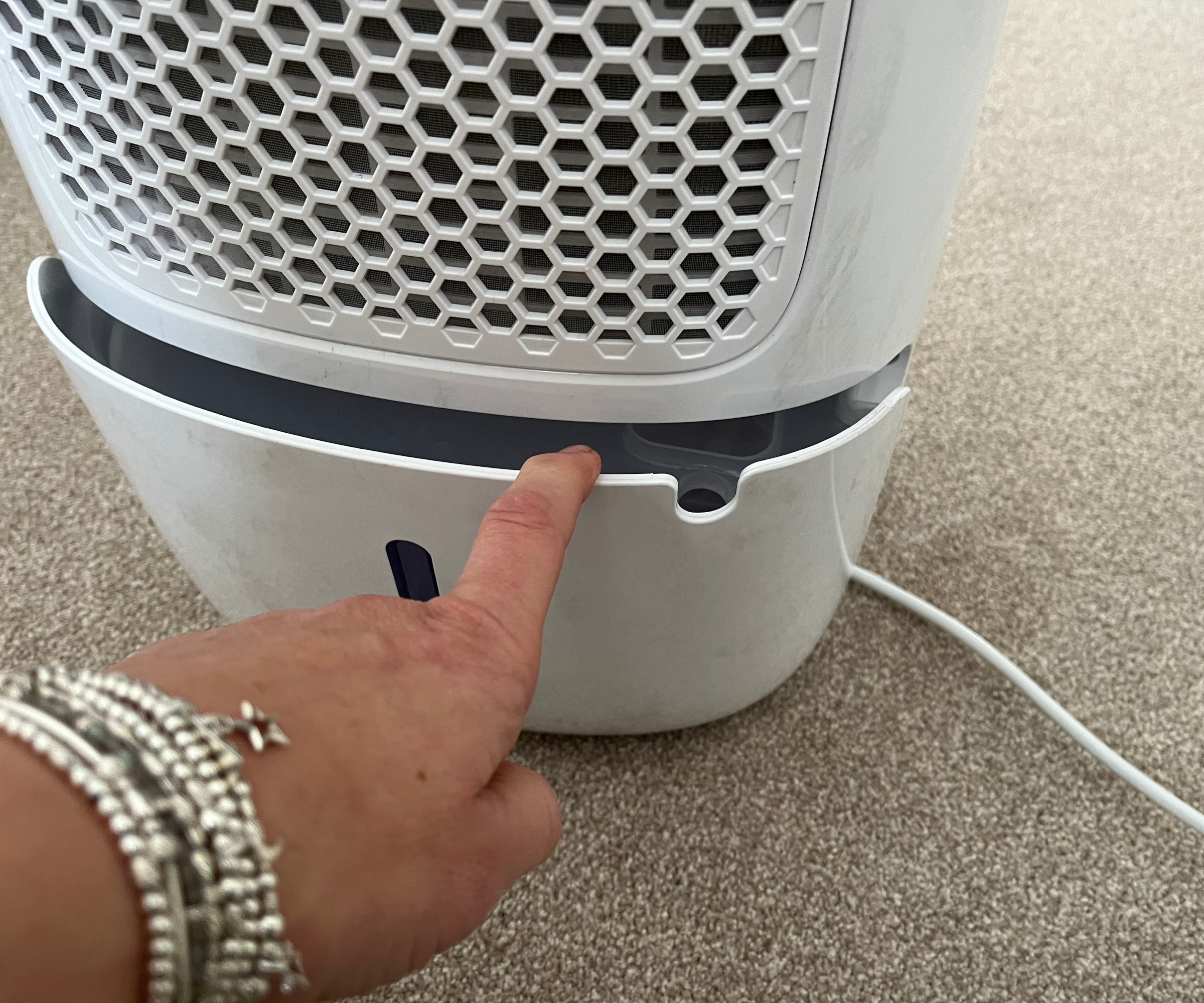 hand pulling water container from rear of dehumidifier