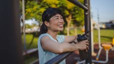 Woman holding bottle containing creatine for women, standing in sunshine outside