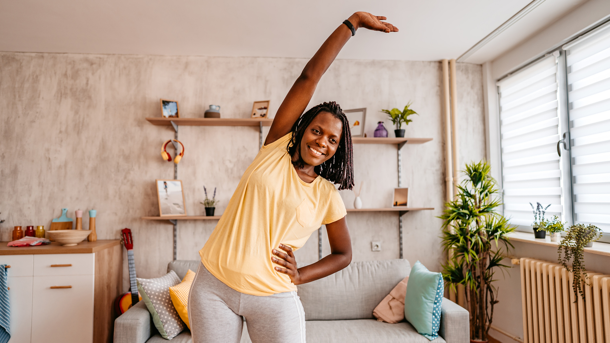 Woman exercising at home, with one arm overhead stretching to the side