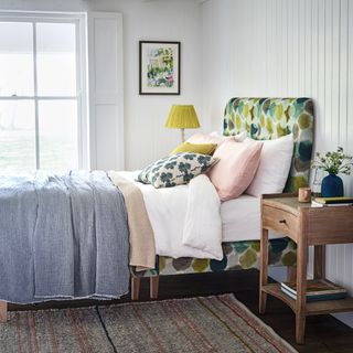 bedroom with colourful cushions rug on floor with white windows