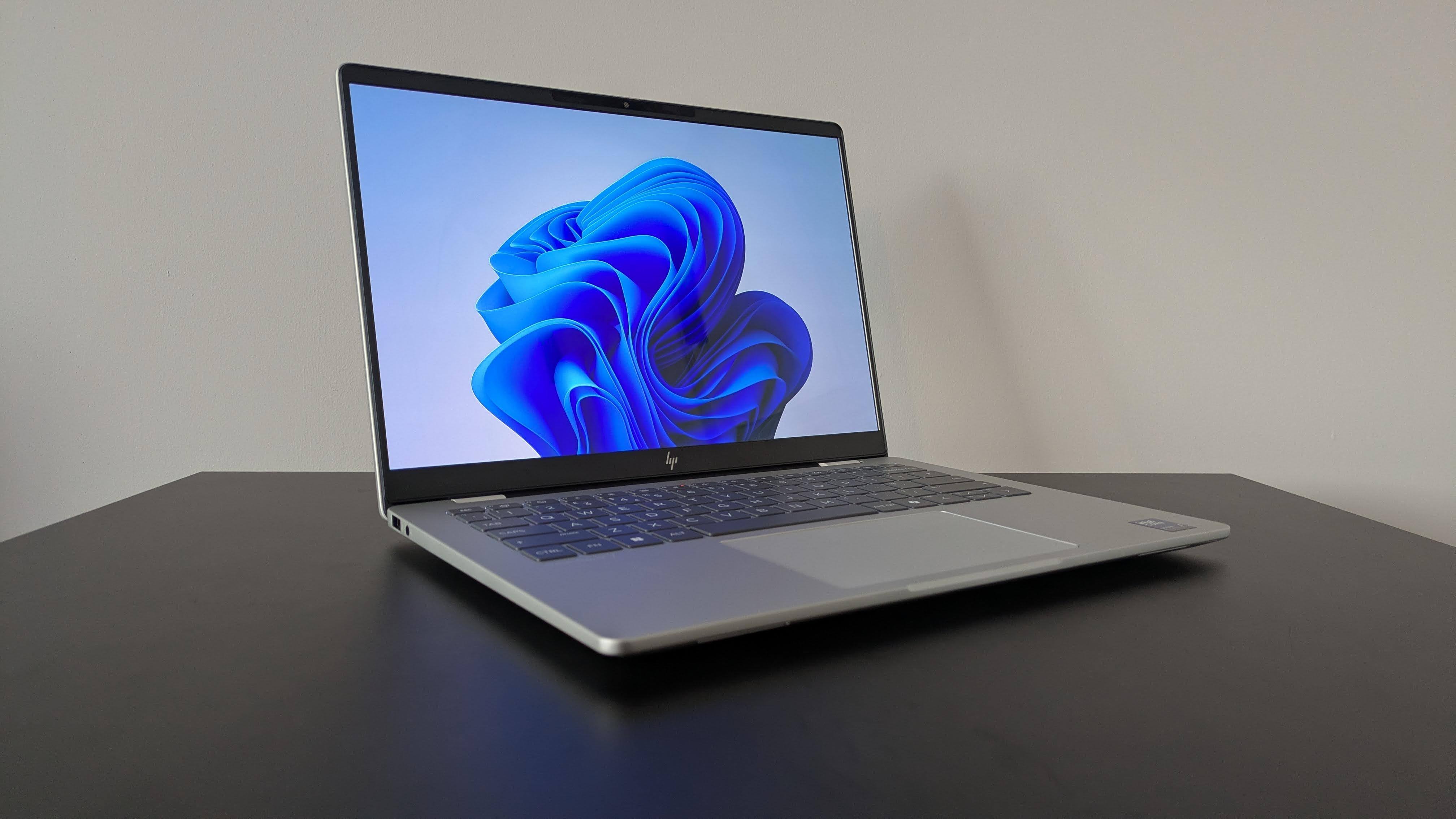 Three-quarter view of HP OmniBook 7 14-inch open on black desk with white wall in background