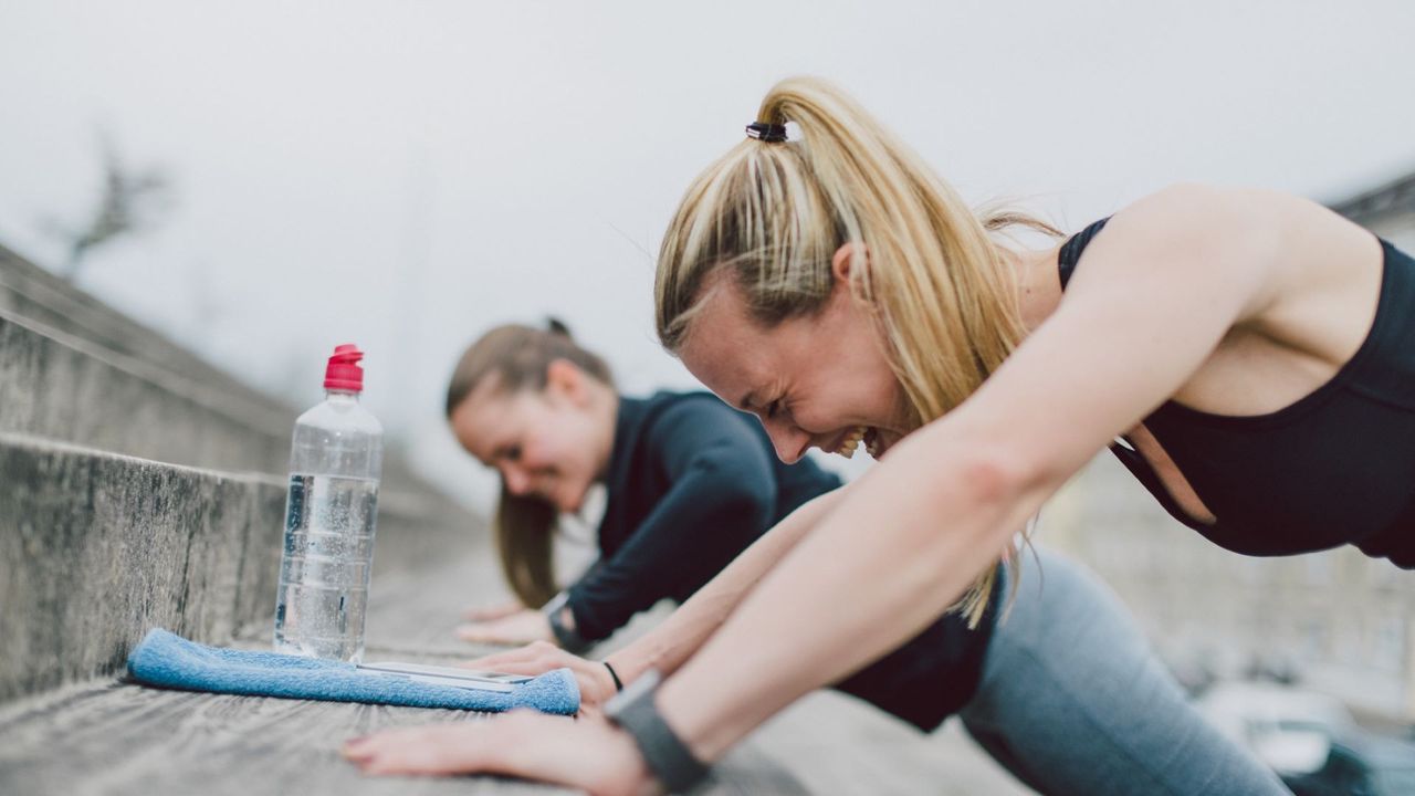 Two women perform incline push ups