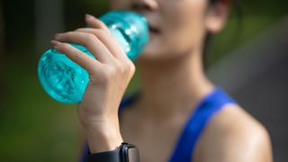 woman drinking water after marathon