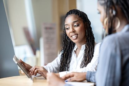 A female businesswoman in a discussion with a bank manager via a tablet computer