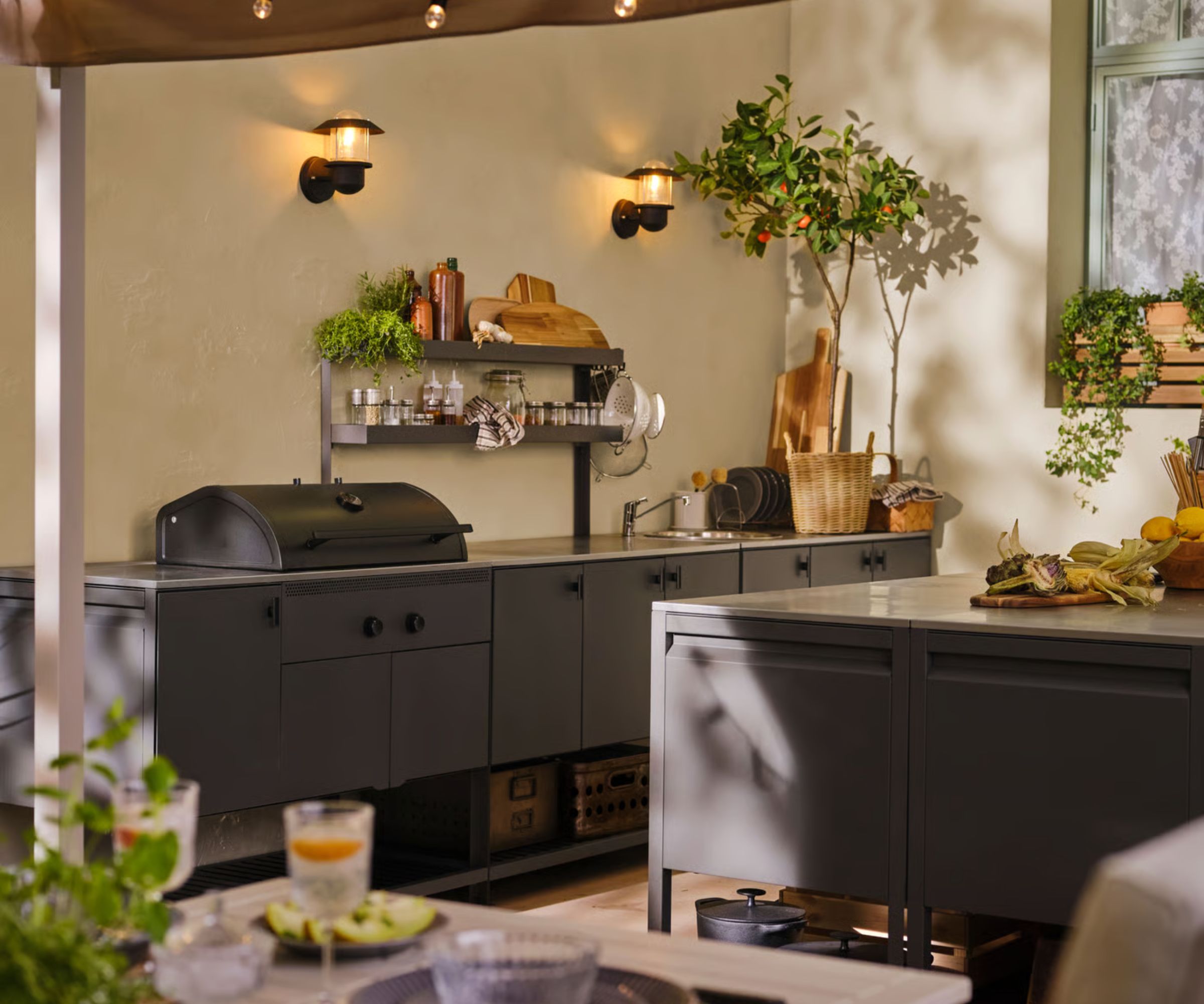 An IKEA modular outdoor kitchen with wall lighting, wall shelves, and a selection of wooden kitchenware