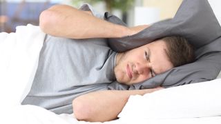 Man covering ears with pillow