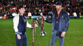 WREXHAM, WALES - APRIL 22: Ryan Reynolds co-owner of Wrexham and Rob McElhenney co-owner of Wrexham with the Vanarama National League Trophy as Wrexham celebrate promotion back to the English Football League during the Vanarama National League match between Wrexham and Boreham Wood at Racecourse Ground on April 22, 2023 in Wrexham, Wales. (Photo by Matthew Ashton - AMA/Getty Images)