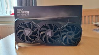 AMD Radeon RX 7900 XT review image showing the GPU standing on its side next to the box