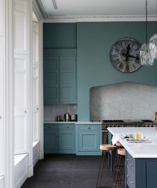 large kitchen with warm blue wall and cabinets, gray floor tiles, white window ledges and ceiling with island unit