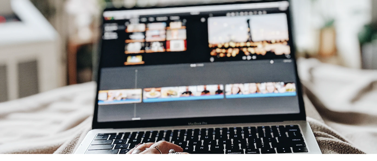 Woman editing video in Apple iMovie on a MacBook in a brightly lit bedroom