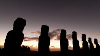 several statues line up beneath a partly cloudy sky