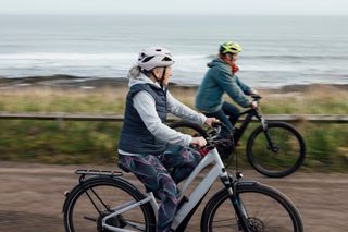 Two cyclists enjoying e-bikes along the coast