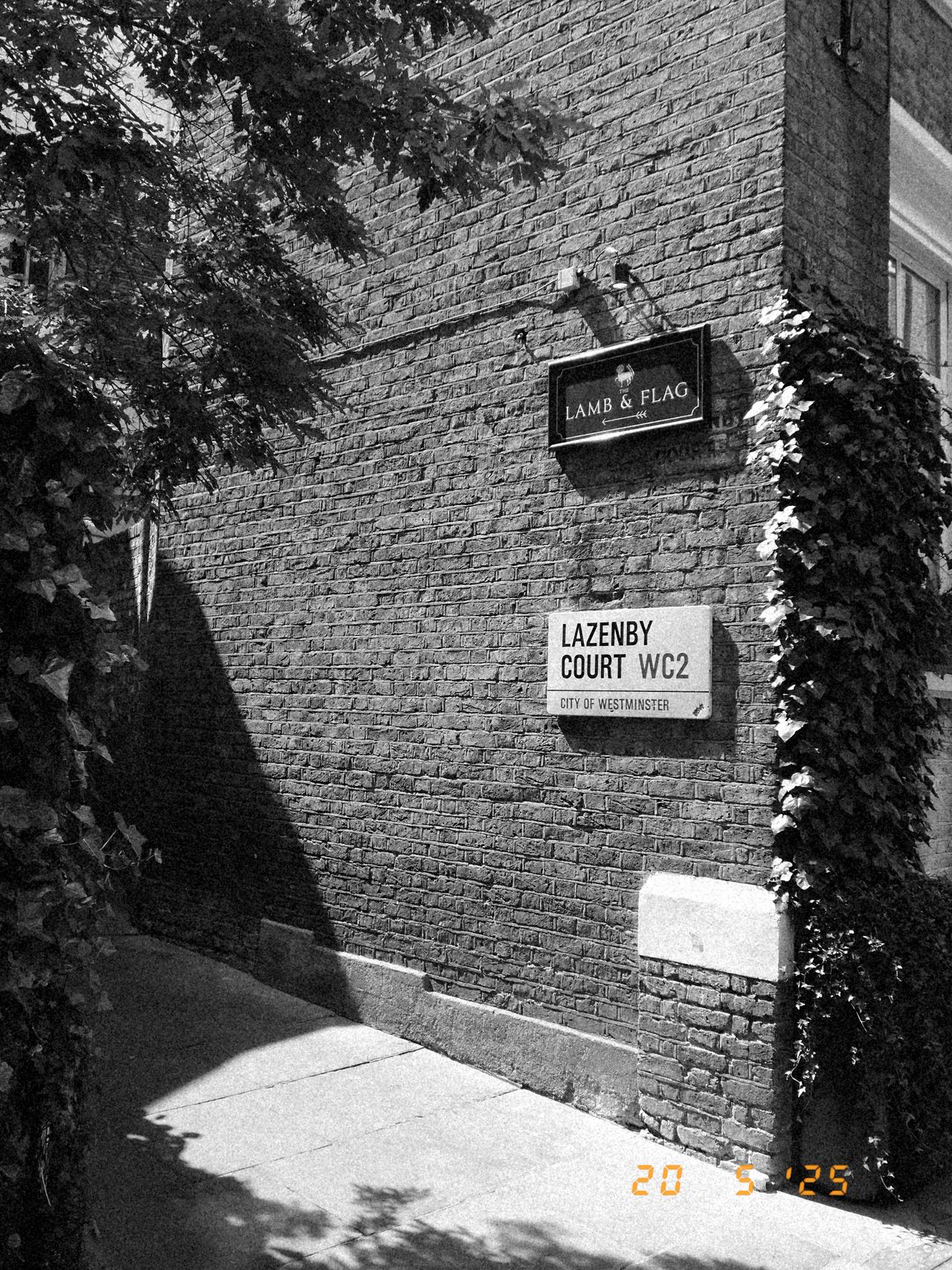 An alleyway in London with street signs on a brick wall