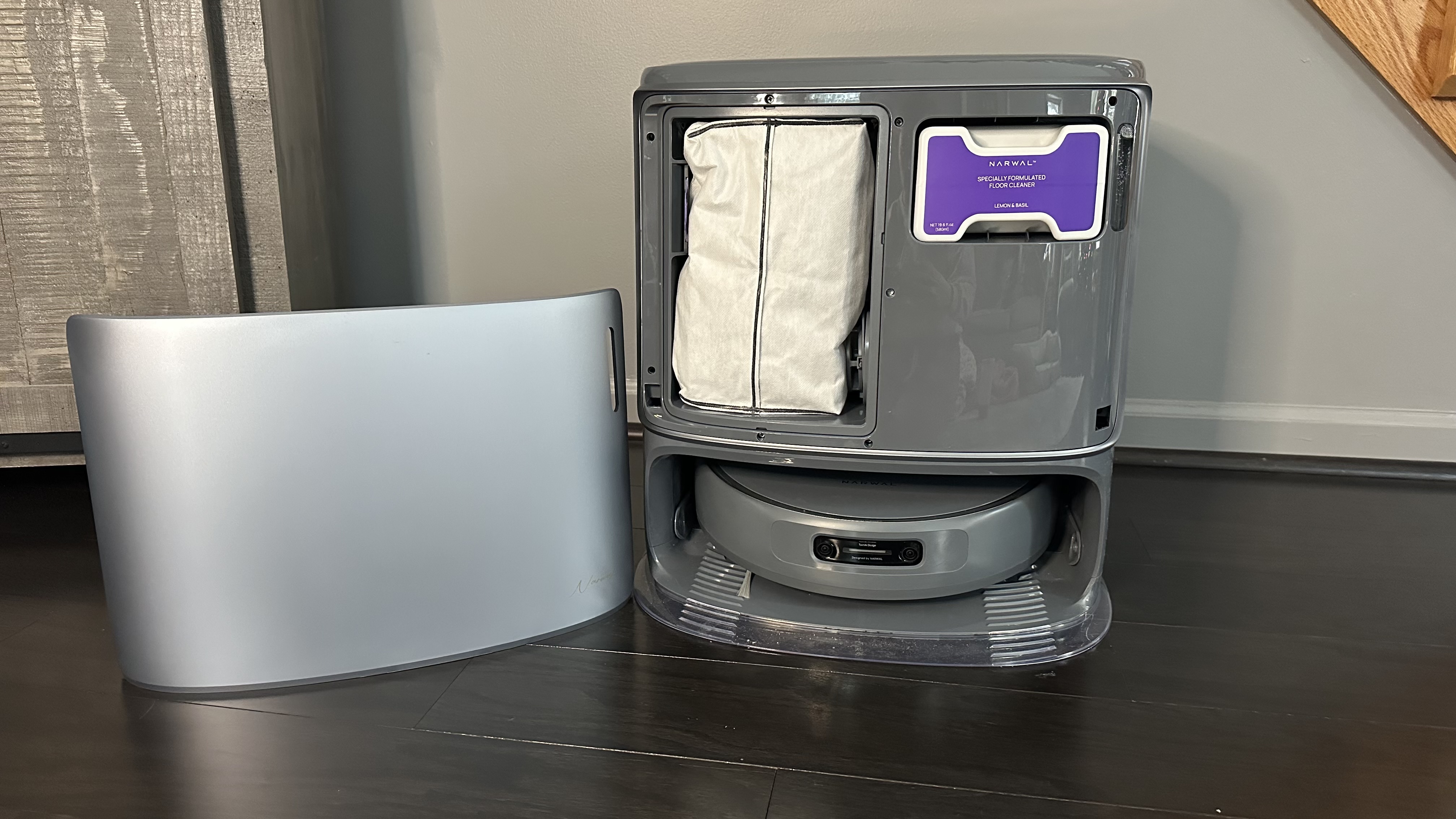 Magnetic front cover of base station removed revealing detergent and dust bag