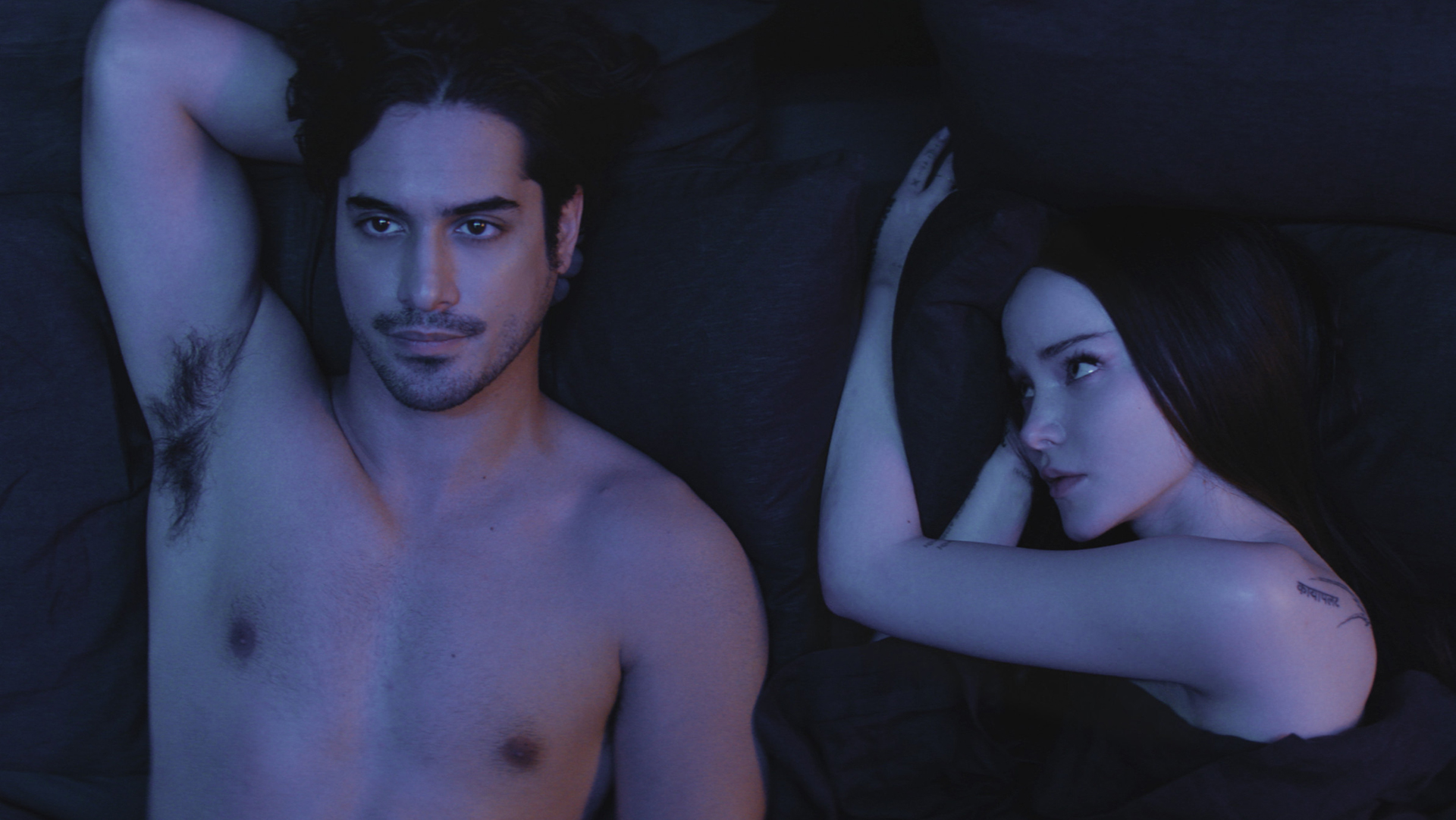 Oliver lying on his back and Ciara lies on her side looking at him in bed in 56 Days