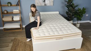 A tester sits on the edge of the Saatva Classic mattress to test its support.