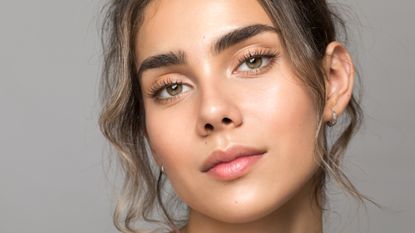 eyebrow tinting - image of woman looking into the camera with beautiful glowy skin and groomed brows