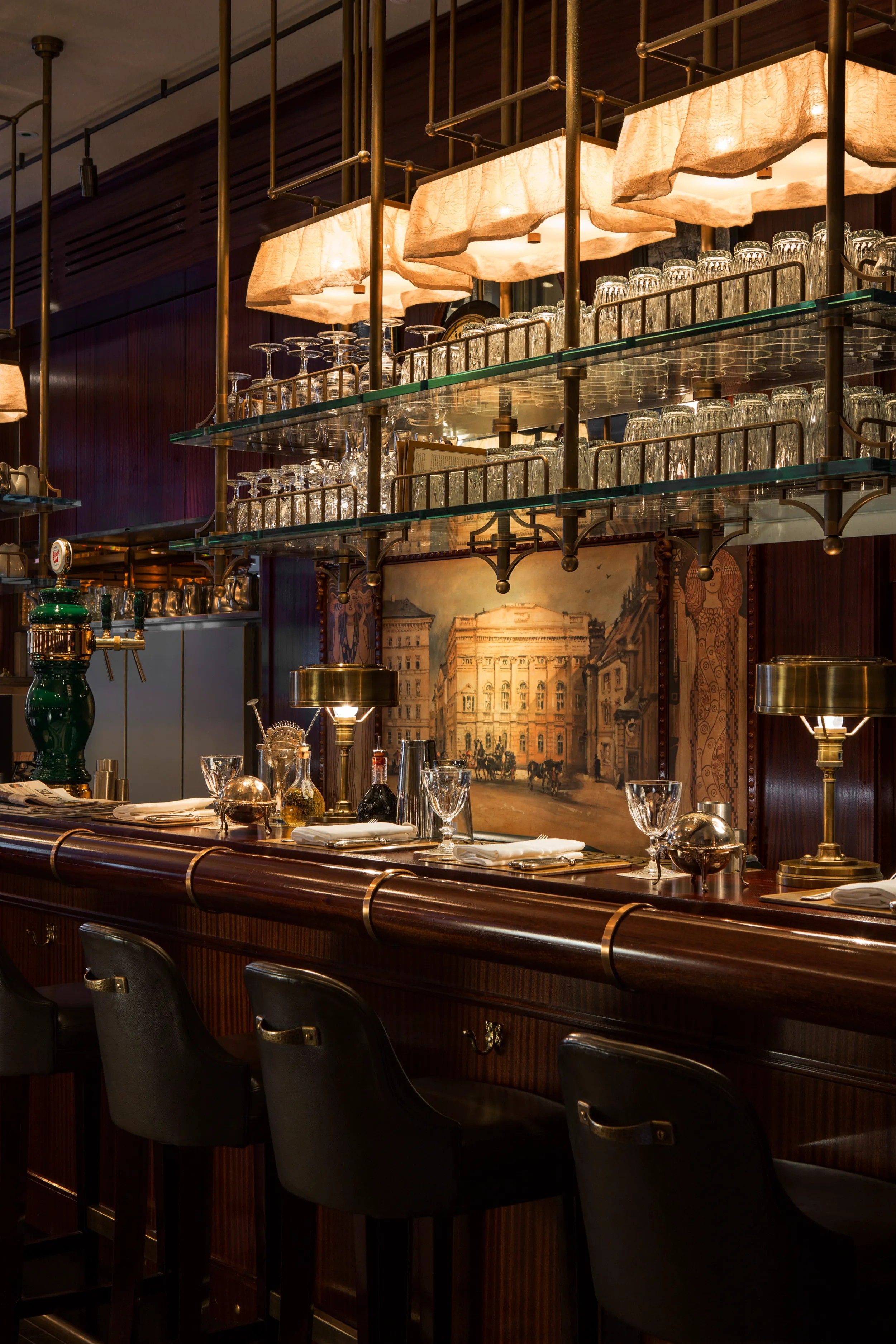 A Vienna-style, Art Deco cafe with gilded framed artworks, wooden furniture, and glassy details.