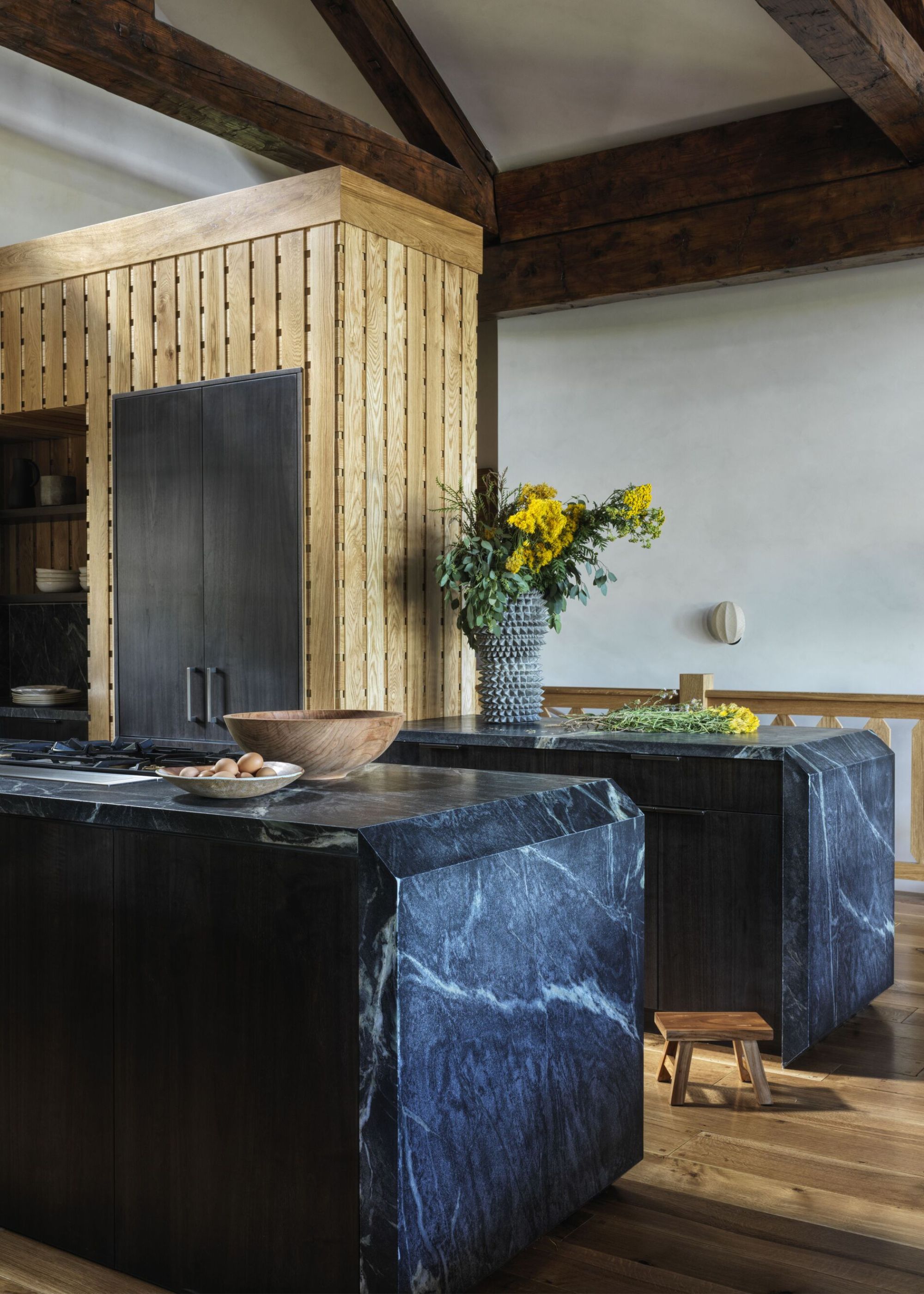 Two soapstone kitchen countertops with veins running around it. One of kitchen countertop is a stove and bowls and on the other is a vase with yellow flowers inside