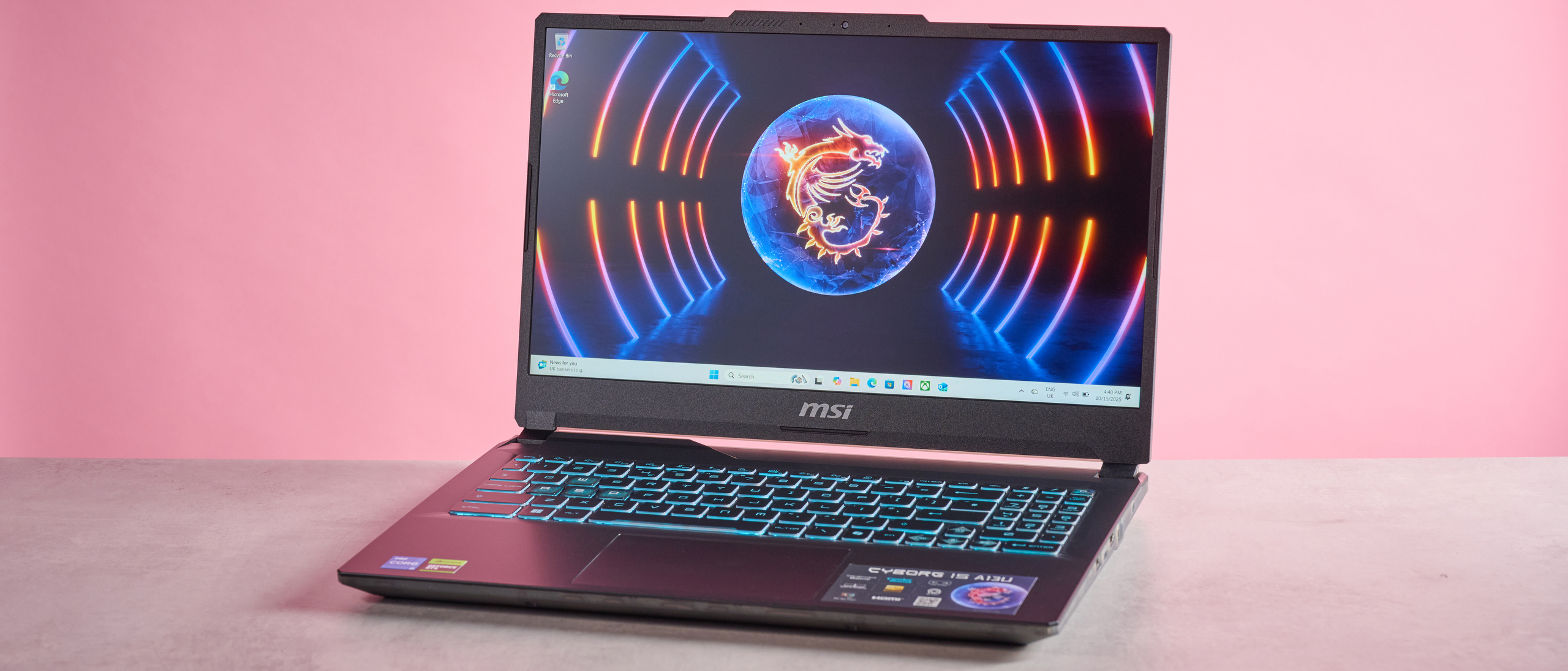 Three-quarter view of MSI Cyborg 15 open on desk on a pink background 
