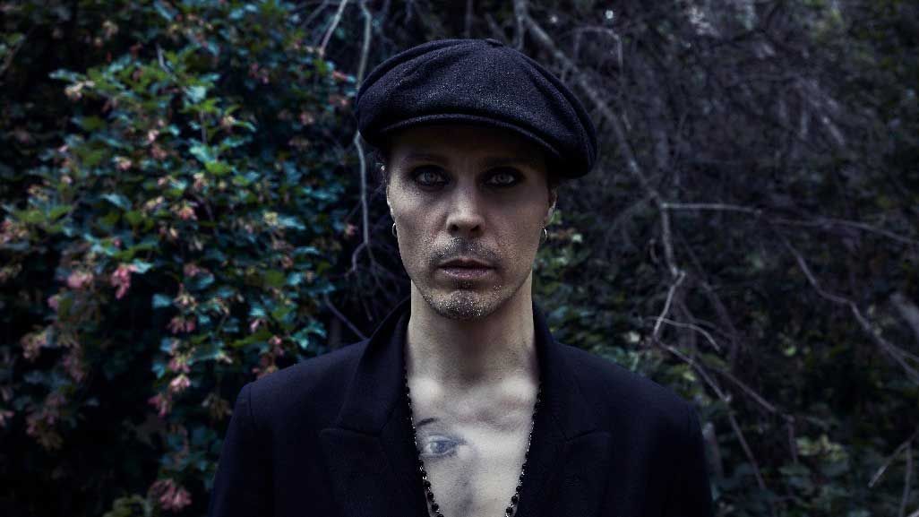 Ville Valo standing in front of a hedge