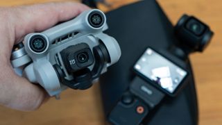 DJI Mini 3 Pro being used as a gimbal camera next to DJI Osmo Pocket 3 as a potential moneysaving alternative with table behind