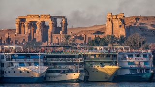 Tourist river cruises parked on the Nile river in front of the temple Kom Ombo. Kom Ombo, Egypt.