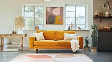 A mustard yellow velvet sofa in a modern open-plan home with white panelled walls